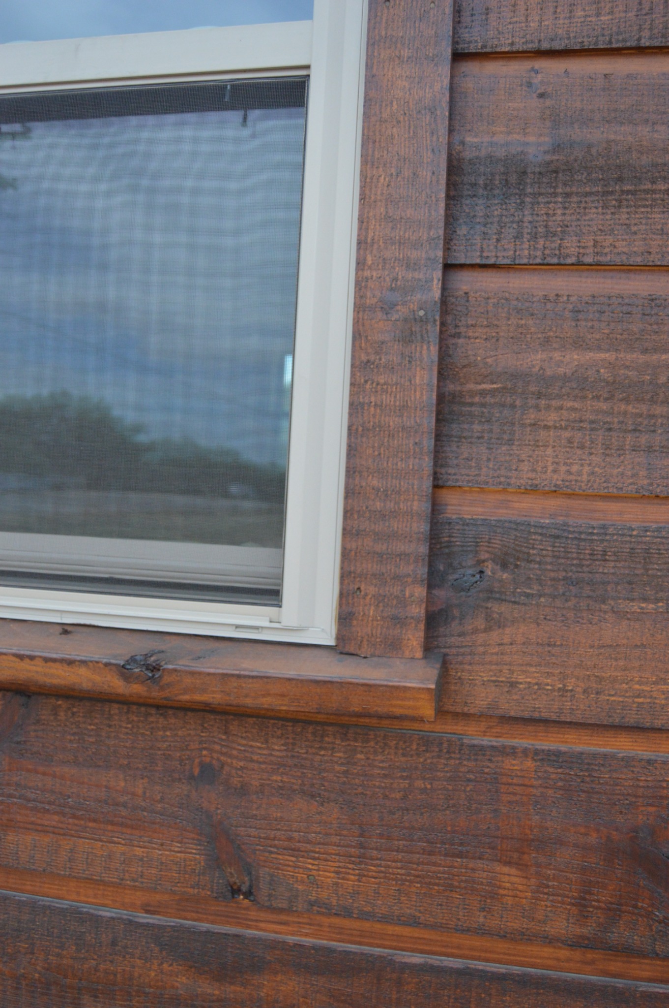 Close view of rough-sawn texture and recessed joints on the cabin’s exterior wood siding